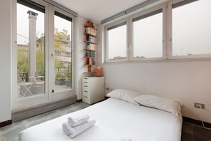 A bedroom with a bed, a bookshelf, a window, and a view of the outside. - GuestHost - APT with large terrace - Calvairate neighborhood (Milano)