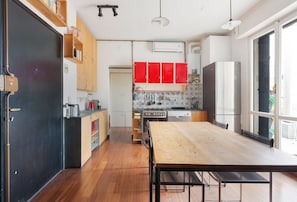 A modern kitchen with wooden cabinets, a large dining table, and a view through the window. - GuestHost - APT with large terrace - Calvairate neighborhood (Milano)