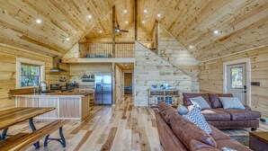 A spacious wooden cabin with a kitchen, dining area, and a cozy living room with a sofa and a bench. - Family Retreat in this Gorgeous Log Cabin overlooking the Arkansas Grand Canyon! (Jasper)