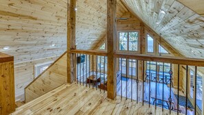 A wooden interior with a sloped ceiling, a balcony with outdoor seating, and a staircase. - Family Retreat in this Gorgeous Log Cabin overlooking the Arkansas Grand Canyon! (Jasper)