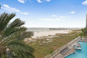 A beach view with a pool and lounge chairs.