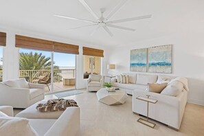A spacious living room with a ceiling fan, a sofa, a coffee table, and a view of the outdoors.