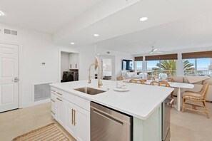 A modern kitchen with a central island, built-in appliances, and a dining area with wicker furniture.
