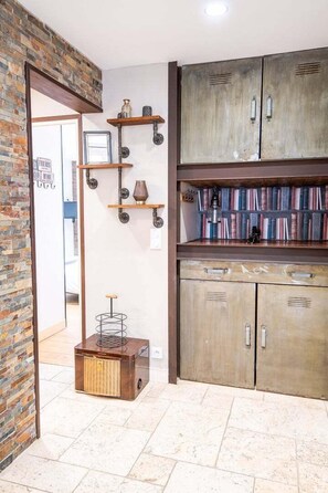 Cozy retreat with a brick wall, wooden cabinet, and metal shelf, featuring a vintage radio and tile flooring.