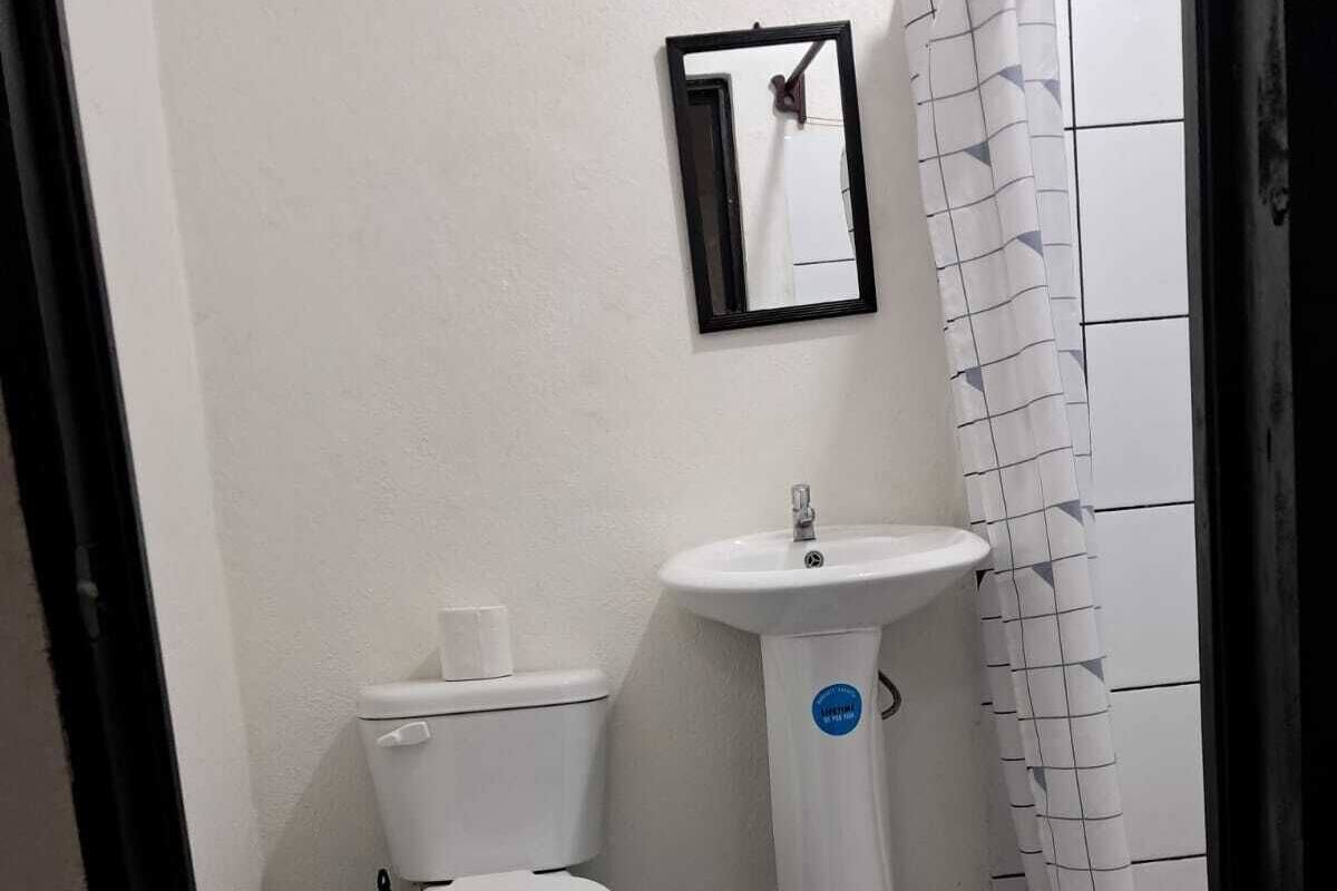 Pieni kylpyhuone, jossa on wc, pesuallas ja laatoitettu lattia.