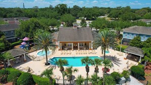 A resort with a swimming pool, lounge chairs, and palm trees.