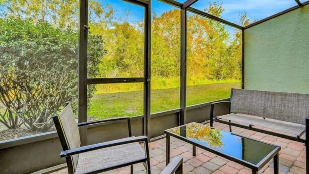 A conservatory with a glass roof, two chairs, and a small table.