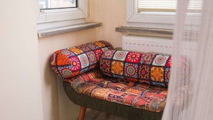 Un sofá de esquina con tapicería de estampado colorido, ubicado frente a una pared con ventana y radiador.