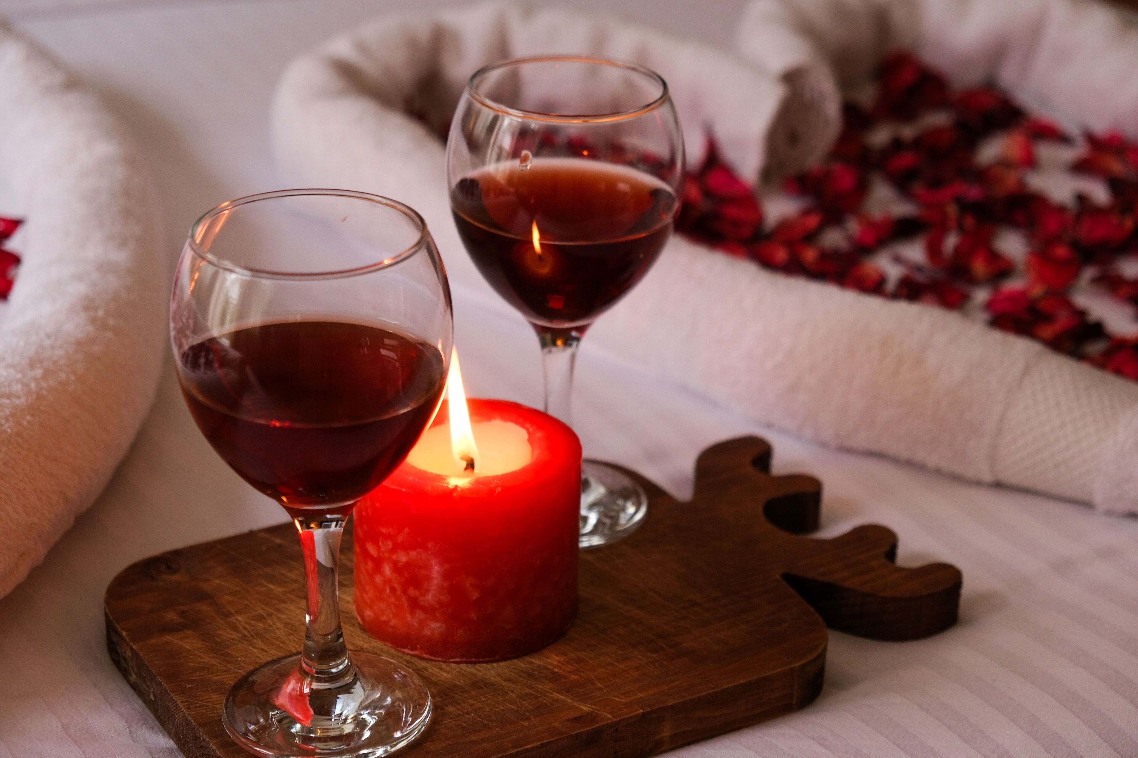 Deux verres à vin et une bougie allumée sur un plateau en bois.