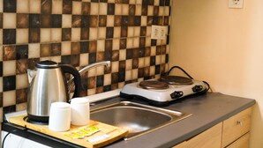 Una cocina con salpicadero a cuadros, una tetera, una estufa, un lavabo y armarios de madera.