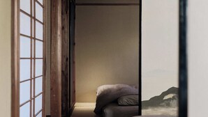 A traditional Japanese room with tatami flooring, a low bed, and a sliding door with a view of mountains. - CraftFlat Asakusa 3 bdr House -Stay Local, Stay Stylish (Sumida City)