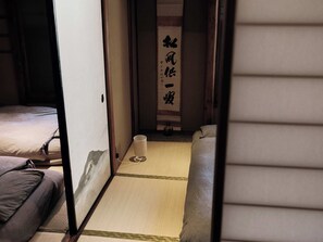 Perinteinen japanilainen huone, jossa on tatamimatto, matala pöytä ja sänky, jossa on tyyny.