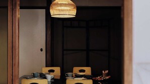 A traditional Japanese-style dining room with tatami flooring, a low table, and wooden chairs. - CraftFlat Asakusa 3 bdr House -Stay Local, Stay Stylish (Sumida City)