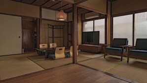 A traditional Japanese-style room with tatami flooring, a low table with cushions, a television, and a sofa. - CraftFlat Asakusa 3 bdr House -Stay Local, Stay Stylish (Sumida City)