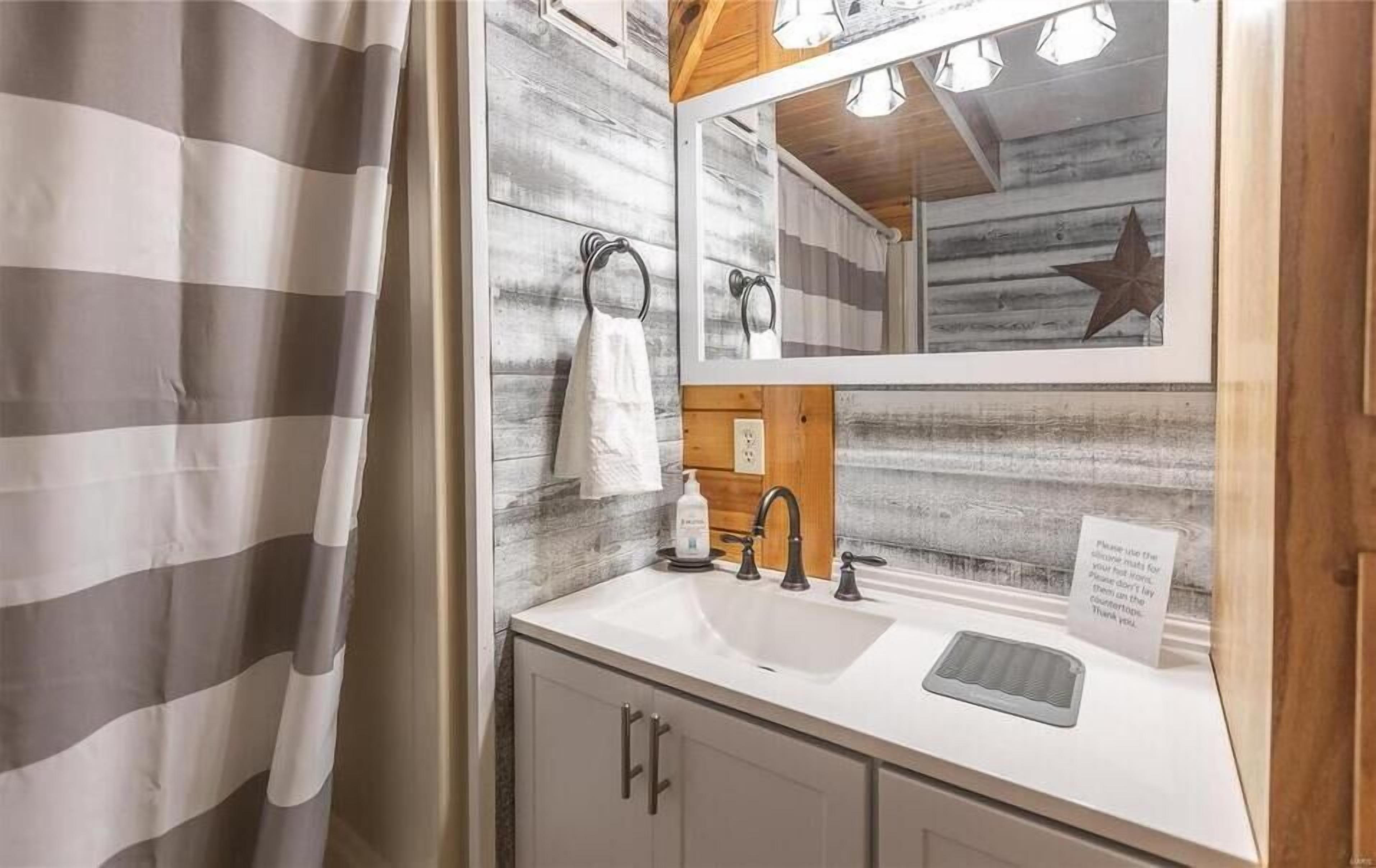 A bathroom with a white sink, wooden wall paneling, a towel rack, and a star decoration.