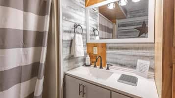 A bathroom with a white sink, wooden wall paneling, a towel rack, and a star decoration.