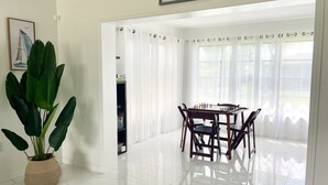 Ein helles Zimmer mit Esstisch und Stühlen, einer großen Topfpflanze und einem Schild mit der Aufschrift 'Welcome to Our Beach House Englewood Beach'.