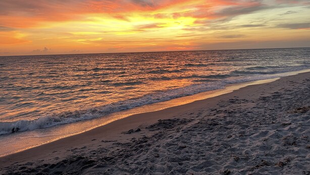 Ein Strand mit Sonnenuntergang über dem Ozean.