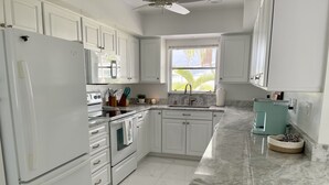 Eine moderne Küche mit weißen Schränken, einem Edelstahl-Kühlschrank, einem eingebauten Backofen und einer Kaffeemaschine.