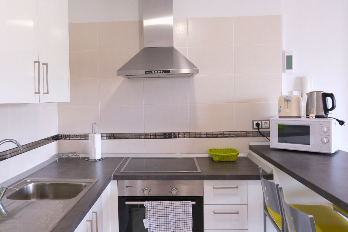 A kitchen with stainless steel appliances, a microwave, a kettle, and a toaster.
