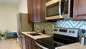 Une cuisine moderne avec des meubles en bois, des appareils électroménagers en acier inoxydable et un revêtement mural décoratif.