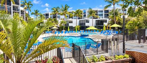 Un resort con piscina, lettini e palme.