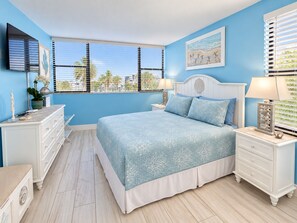 A bedroom with a bed, nightstands, a dresser, and a window with blinds. - Sunsets and Turtles – Key Largo Moon Bay Condo – Boat Slip/Lift Optional (Key Largo)