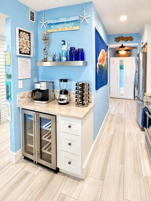 Eine Küche mit blauer Wand, einer Kaffeemaschine, einem Mixer und einem Kühlschrank.