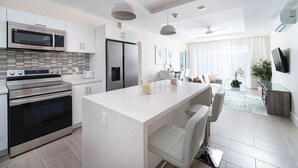 Una cocina moderna con electrodomésticos de acero inoxidable, una isla central con asientos y un comedor con un amplio ventanal.