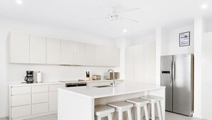 A modern kitchen with white cabinetry, a stainless steel refrigerator, and a central island with bar stools. - Incredible villa, beach club access- Whitehaven  (2 bed) (Westmoreland)