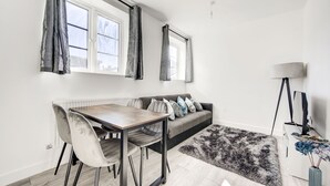 Una sala moderna con una mesa de comedor, un sofá gris y un alfombra de pelo alto negro.