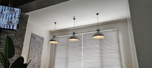 A room with a brick wall, a large window with blinds, and three pendant lights. - Condominium in Kamuning (Lungsod Quezon)