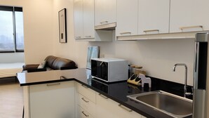 Ett modernt kök med vita skåp, en svart bänkskiva, ett kylskåp i rostfritt stål och en inbyggd mikrovågsugn.