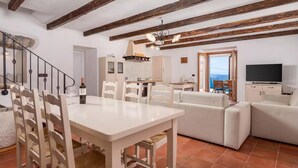 A spacious living area with a dining table and chairs, a sofa set, a kitchen with a stove, and a television. - Amazing home in Labin - Rabac (Labin - Rabac)