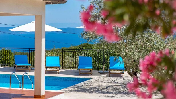 A poolside area with a clear view of the sea, a covered seating area with blue chairs, and a tree with pink flowers. - Amazing home in Labin - Rabac (Labin - Rabac)