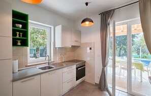 Enjoy cooking in this well-lit kitchen with a large window offering a view of the outdoor pool area.