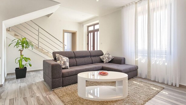 A modern living room with a grey sofa, a round coffee table, and a potted plant. - Awesome home in Liznjan (Liznjan)
