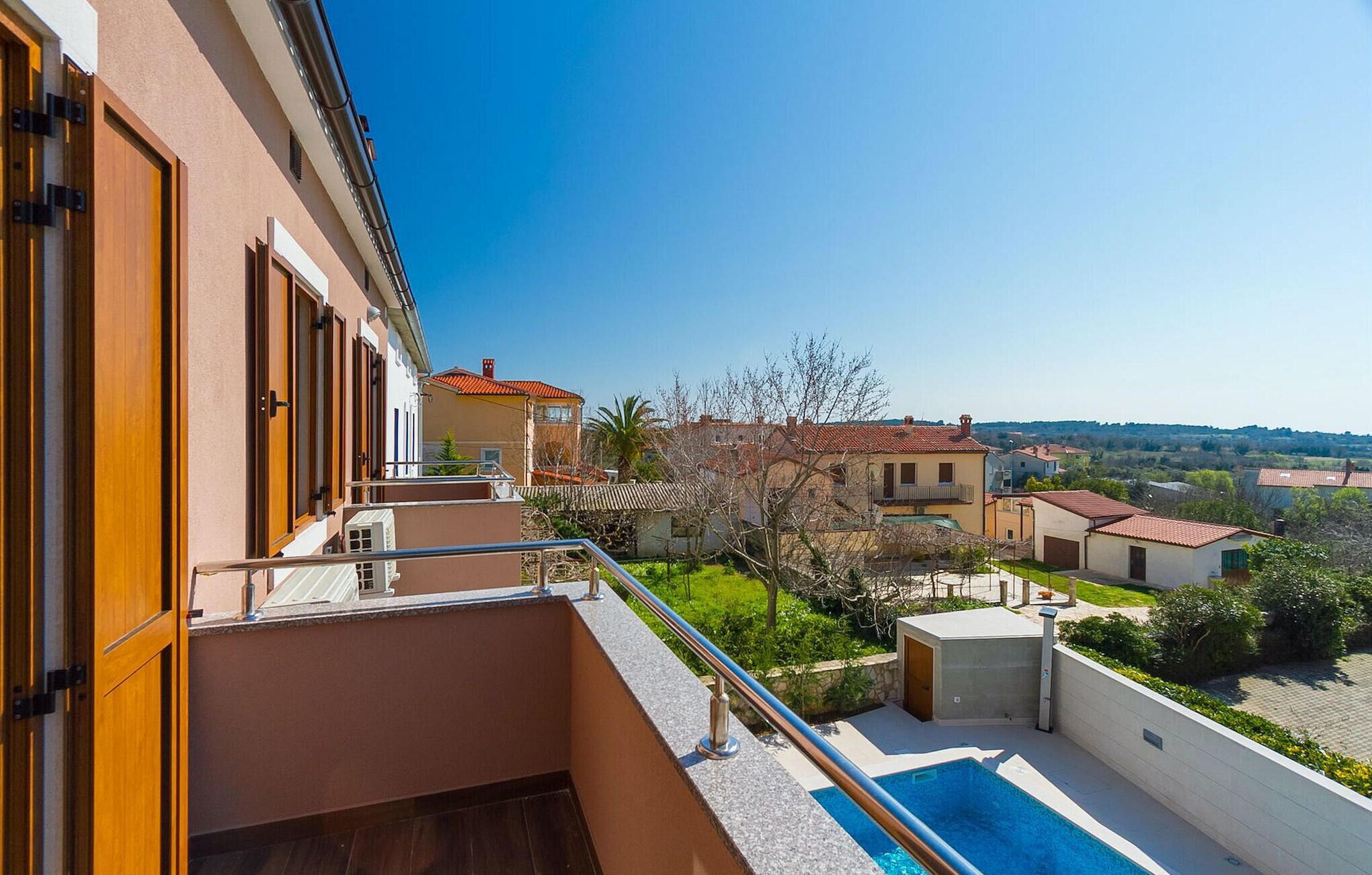 A residential building with a balcony overlooking a swimming pool and a garden.