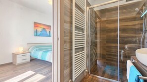 A modern bathroom with a glass shower enclosure, a wooden floor, and a visible sink. - Awesome home in Liznjan (Liznjan)
