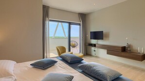 A modern hotel room with a large bed, a TV, a small seating area, and a balcony with a view. - Stunning home in Porec with sauna (Porec)