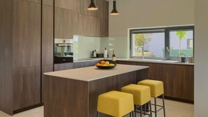A modern kitchen with a central island, wooden cabinetry, pendant lighting, and a view of the outdoors. - Stunning home in Porec with sauna (Porec)