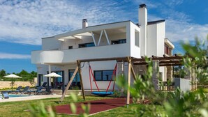 A modern two-story house with a swimming pool, outdoor seating, and a swing set. - Stunning home in Porec with sauna (Porec)