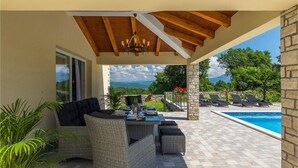 Eine Terrasse im Freien mit Korbmöbeln, einem Pool und Blick auf die Landschaft.