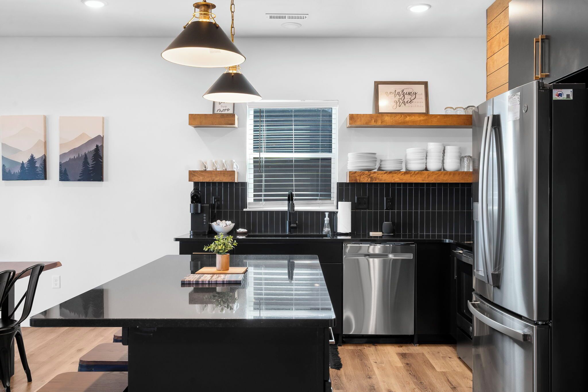 A modern kitchen with a central island, stainless steel appliances, and black cabinetry.