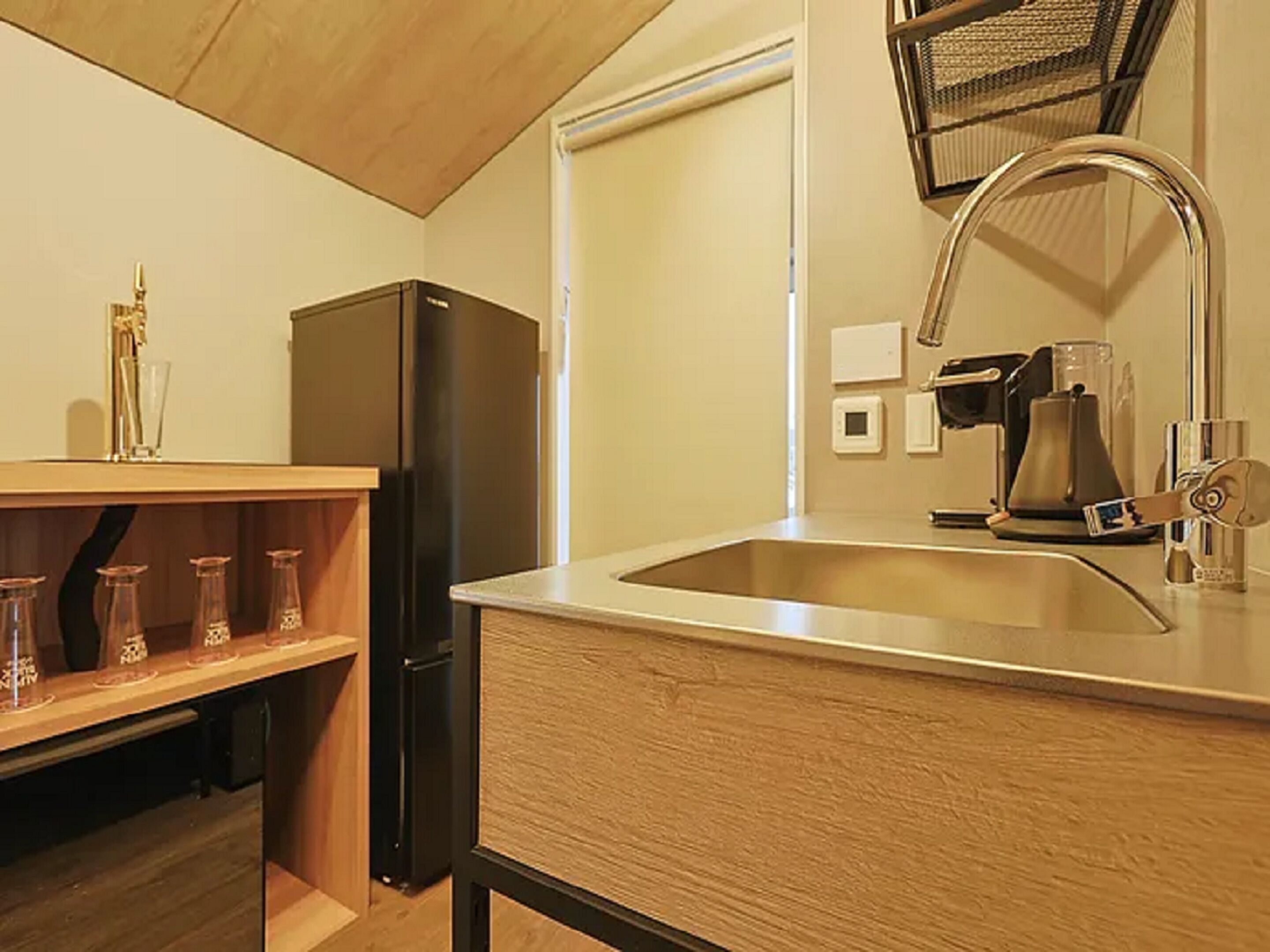 A kitchen with a stainless steel sink, a coffee machine, and a black refrigerator.
