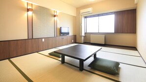 A traditional Japanese room with tatami flooring, a low table, cushions, a television, and a window with a view. - Hotel Alpen Blick (Myoko)