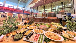A buffet with various dishes and a large window overlooking a kitchen area. - Hotel Alpen Blick (Myoko)