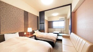 A hotel room with two beds, a sofa, a mirror, and a window. - Hotel Alpen Blick (Myoko)