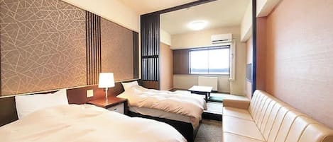 Habitación de hotel con dos camas, un sofá, un espejo y una ventana.