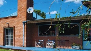 En murbygning med en overdækket terrasse, udendørs møbler og en parabolantenne.
